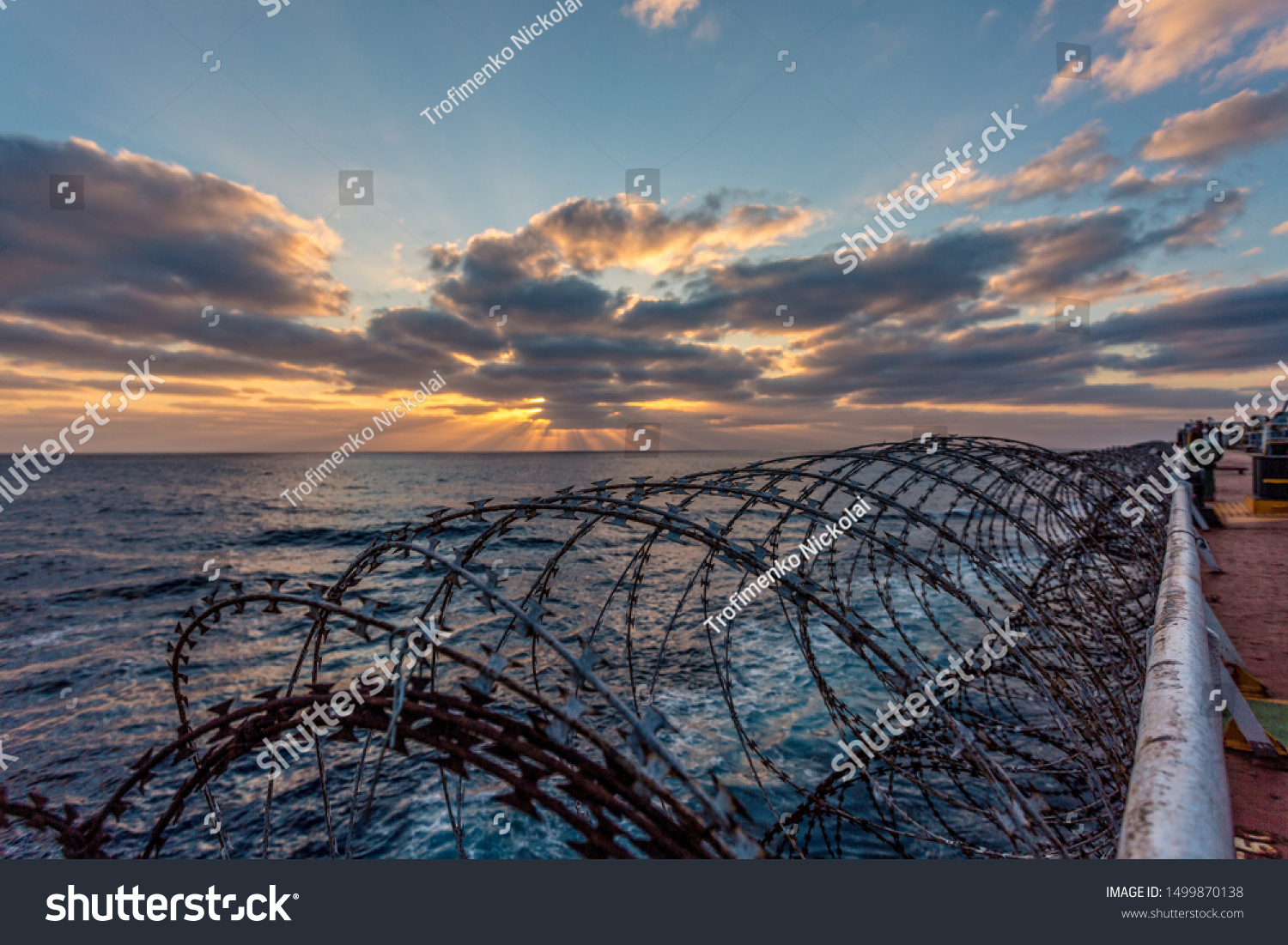 Balker in a pirate area of Africa. The photo shows a barbed wire against a sunset. Barbed wire on merchant ships is installed to protect against pirate attacks. #1499870138