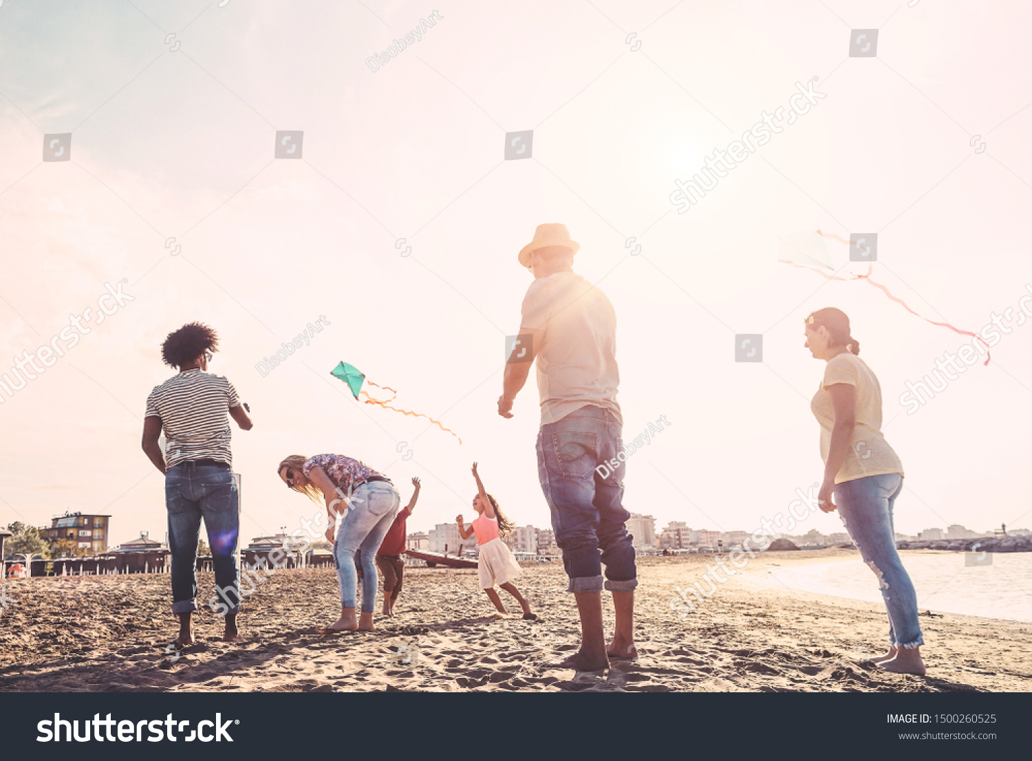 Happy familes flying with kite and having fun on the beach - Parents playing with children outdoor - Travel,love and holidays concept - Main focus on left couple #1500260525