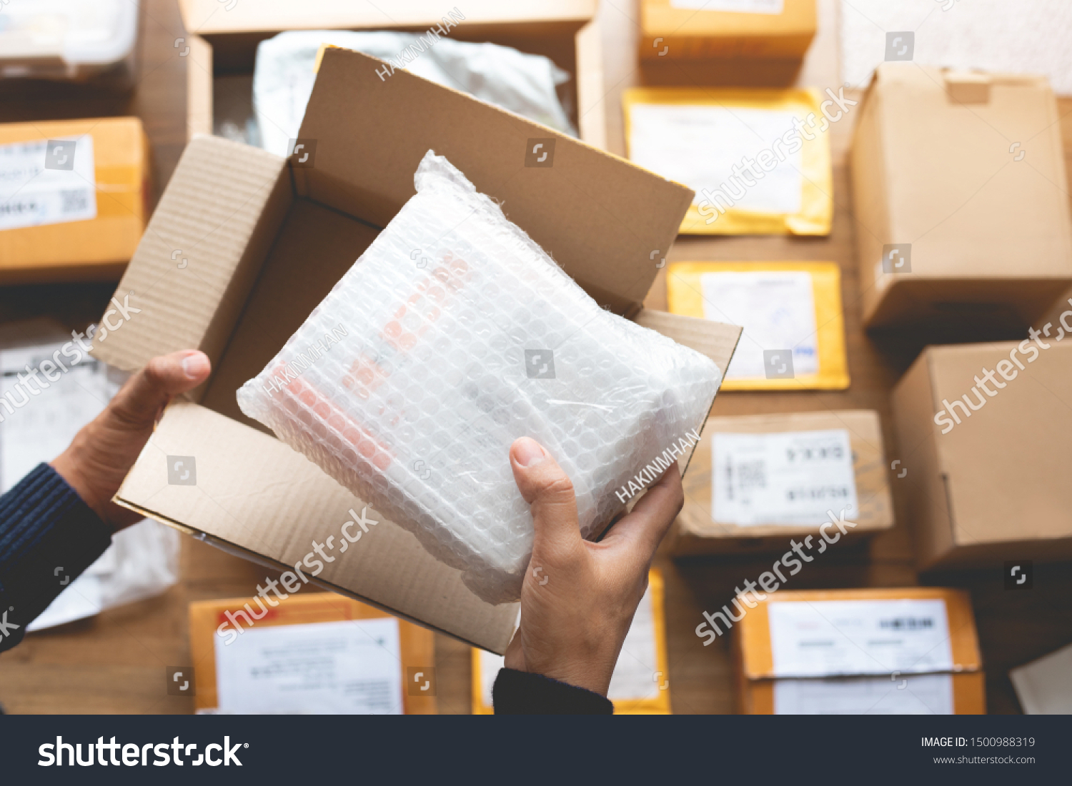 Online shopping concepts with male hand packing some product to brown box on another packet for shipping to customer.Ecommerce,delivery and logistic network.Business retail market #1500988319