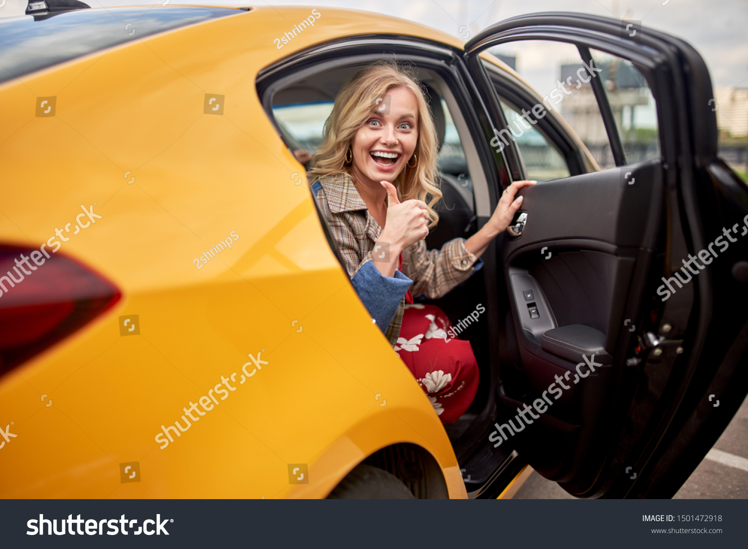 Photo of enthusiastic blonde sitting in back seat of yellow taxi with door open #1501472918