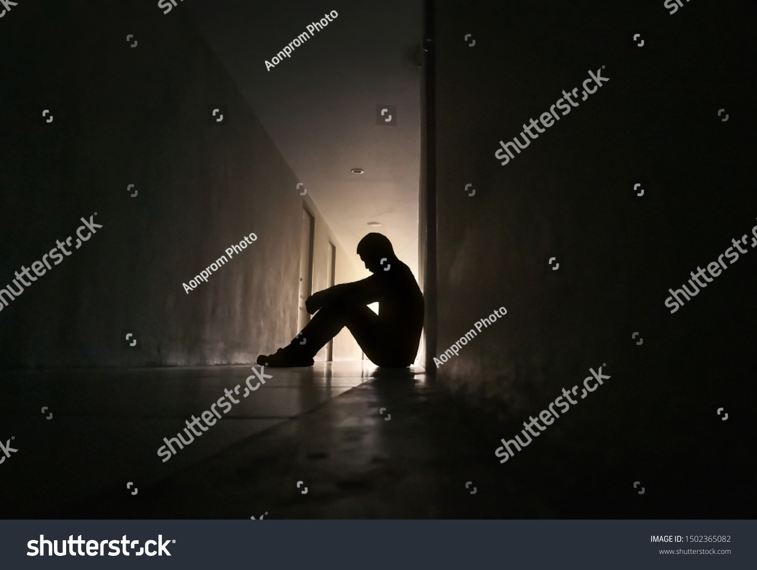 Silhouette of depressed man sitting on walkway of residence building. Sad man, Cry, drama, lonely and unhappy concept. #1502365082
