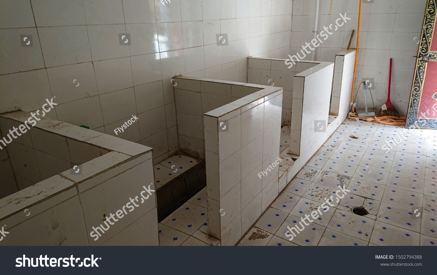 CLOSE UP: Empty public toilets in remote Tibetan town with waist high dividers. Dreary view of smelly squat latrines in China separated by only short walls. Unhygienic restrooms with no privacy. #1502794388