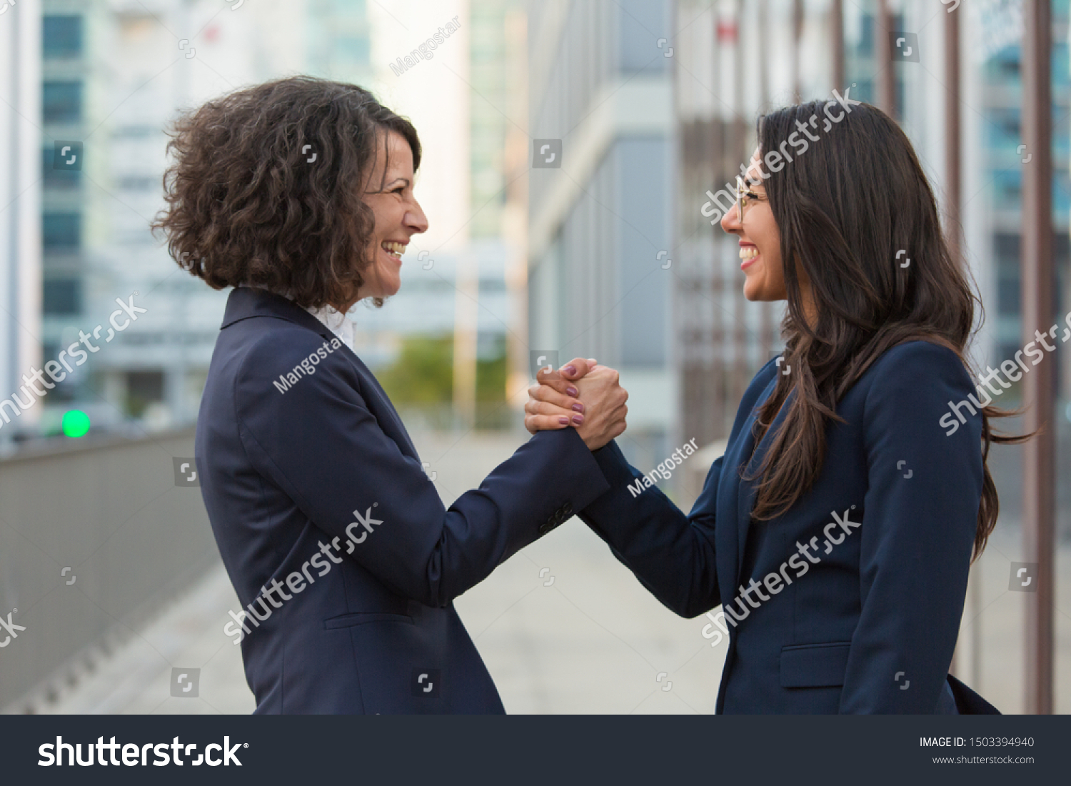 Happy businesswomen celebrating team success. Business ladies giving friendly handshake. Corporate success concept #1503394940