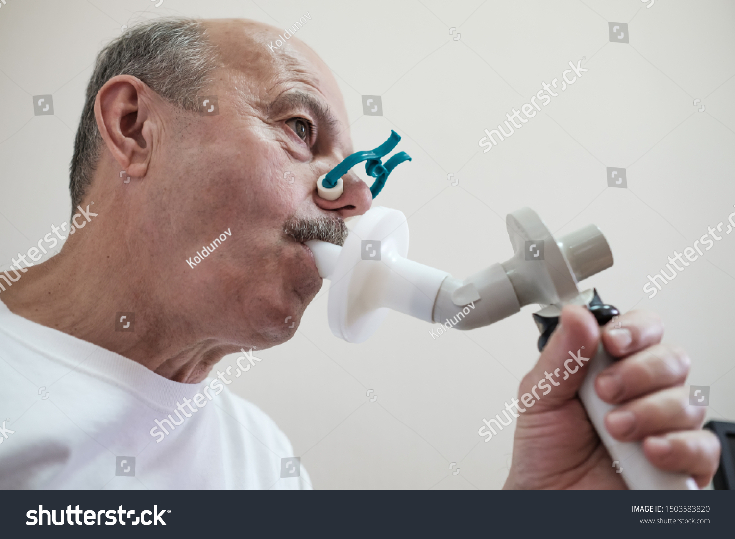 Senior hispanic man man testing breathing function by spirometry. Diagnosis of respiratory function in pulmonary disease
