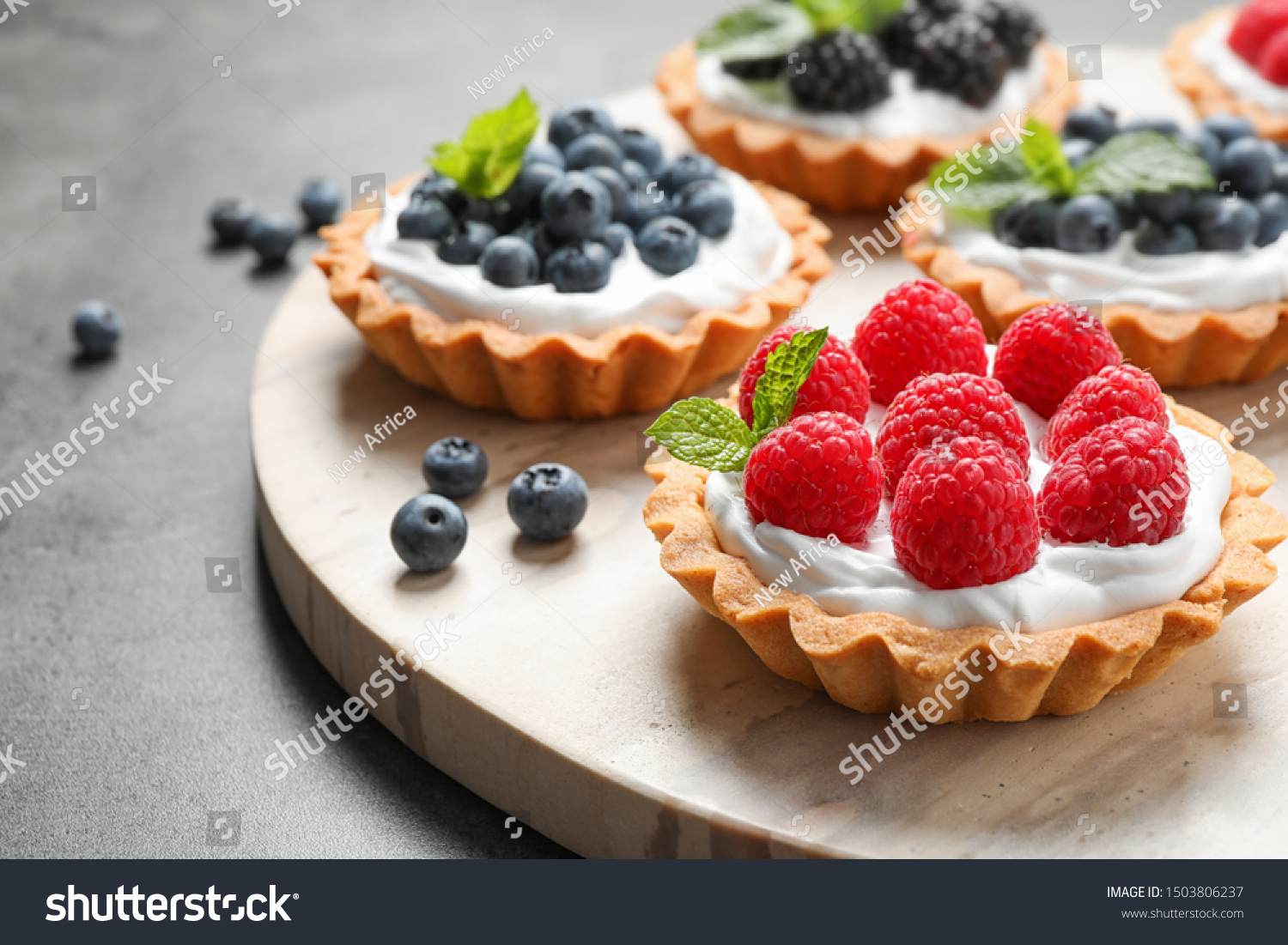 Different berry tarts on light table. Delicious pastries #1503806237