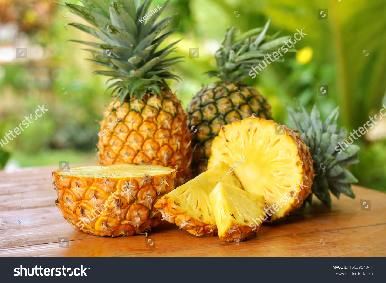 Sliced and half of Pineapple(Ananas comosus) on wooden table with blurred garden background.Sweet,sour and juicy taste.Have a lot of fiber,vitamins C and minerals.Fruits or healthcare concept. #1503954347