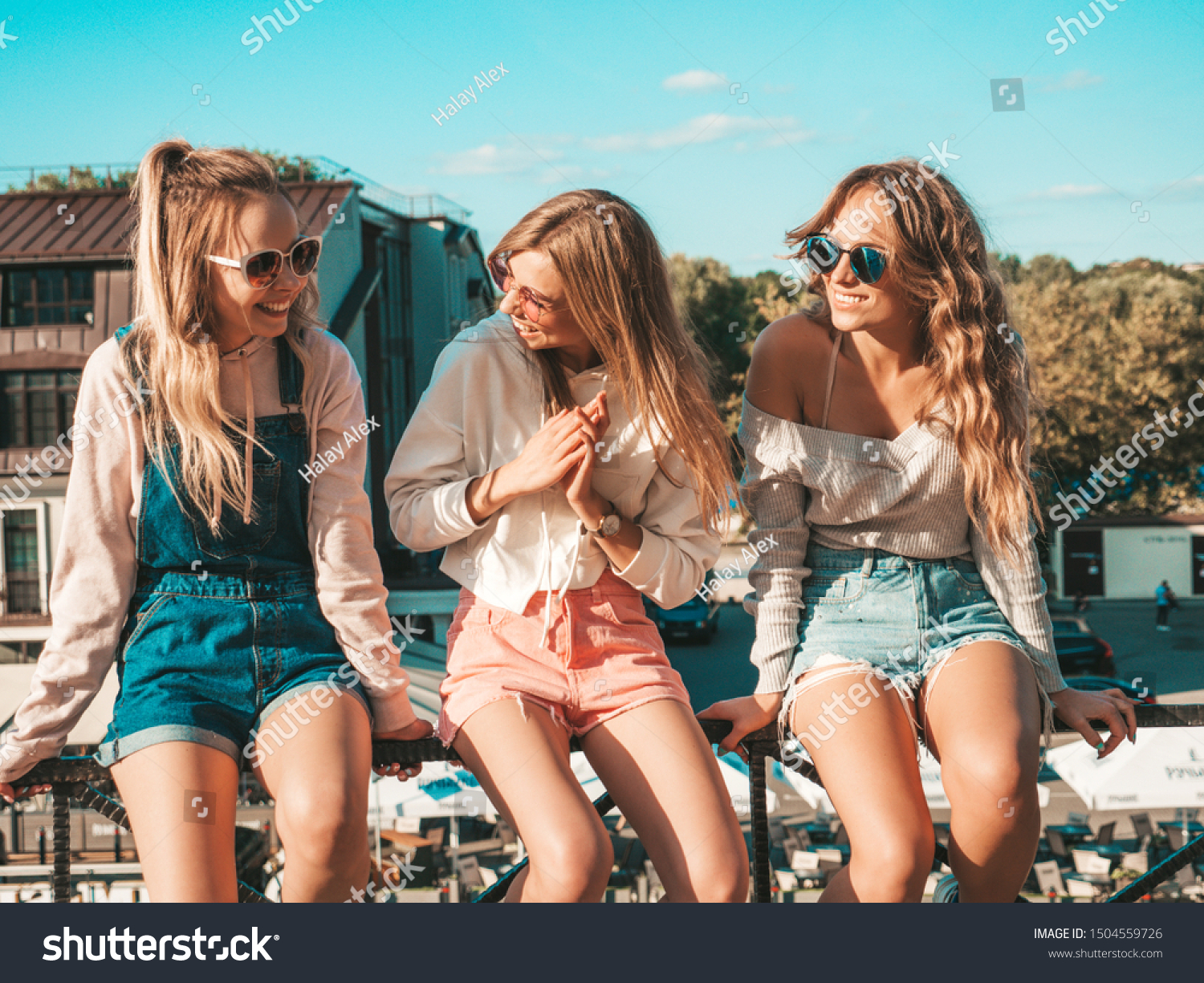 Three young beautiful smiling hipster girls in trendy summer clothes.Sexy women sitting on handrail in the street.Positive models having fun in sunglasses.They communicating and discussing something #1504559726