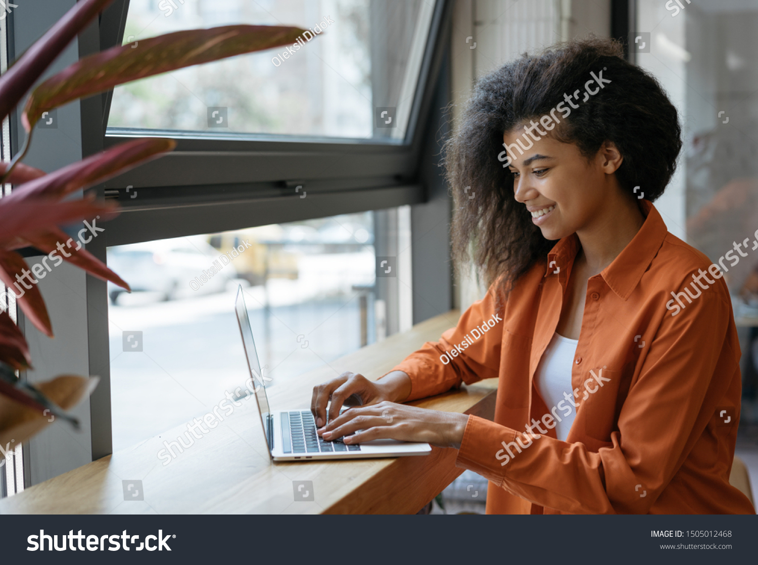Happy African American woman copywriter working freelance project in modern cafe. Businesswoman using laptop, searching information on website. Successful business. Online training courses concept #1505012468