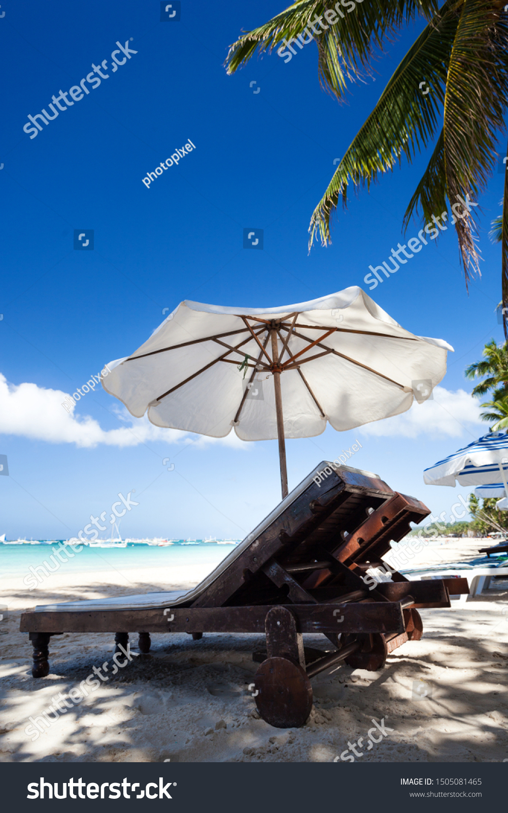Sun umbrella and sunlongers on sandy tropical beach with white sand and turquoise sea water. Travel destinations. Summer vacations #1505081465