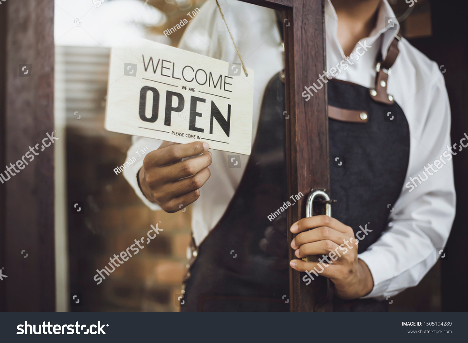 Store owner turning open sign broad through the door glass and ready to service. #1505194289