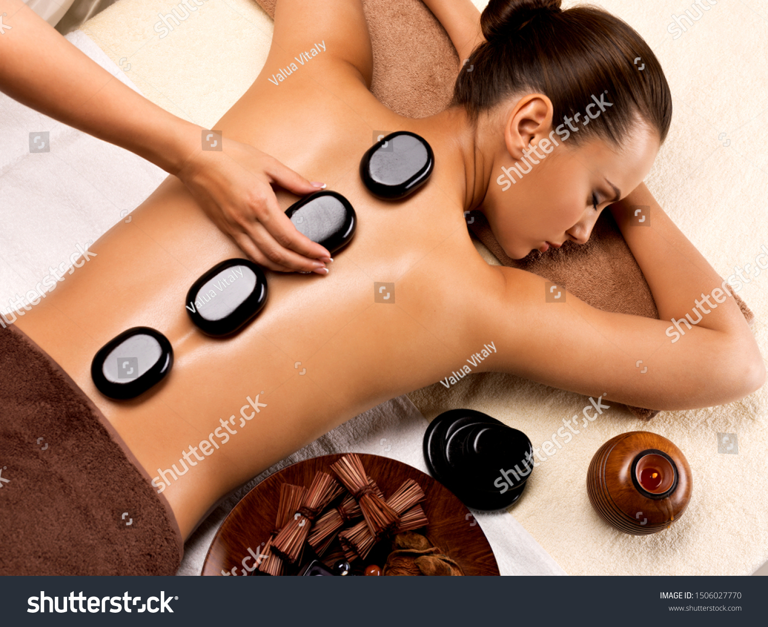 Beautiful woman relaxing in spa salon with hot stones on body. Beauty treatment therapy #1506027770