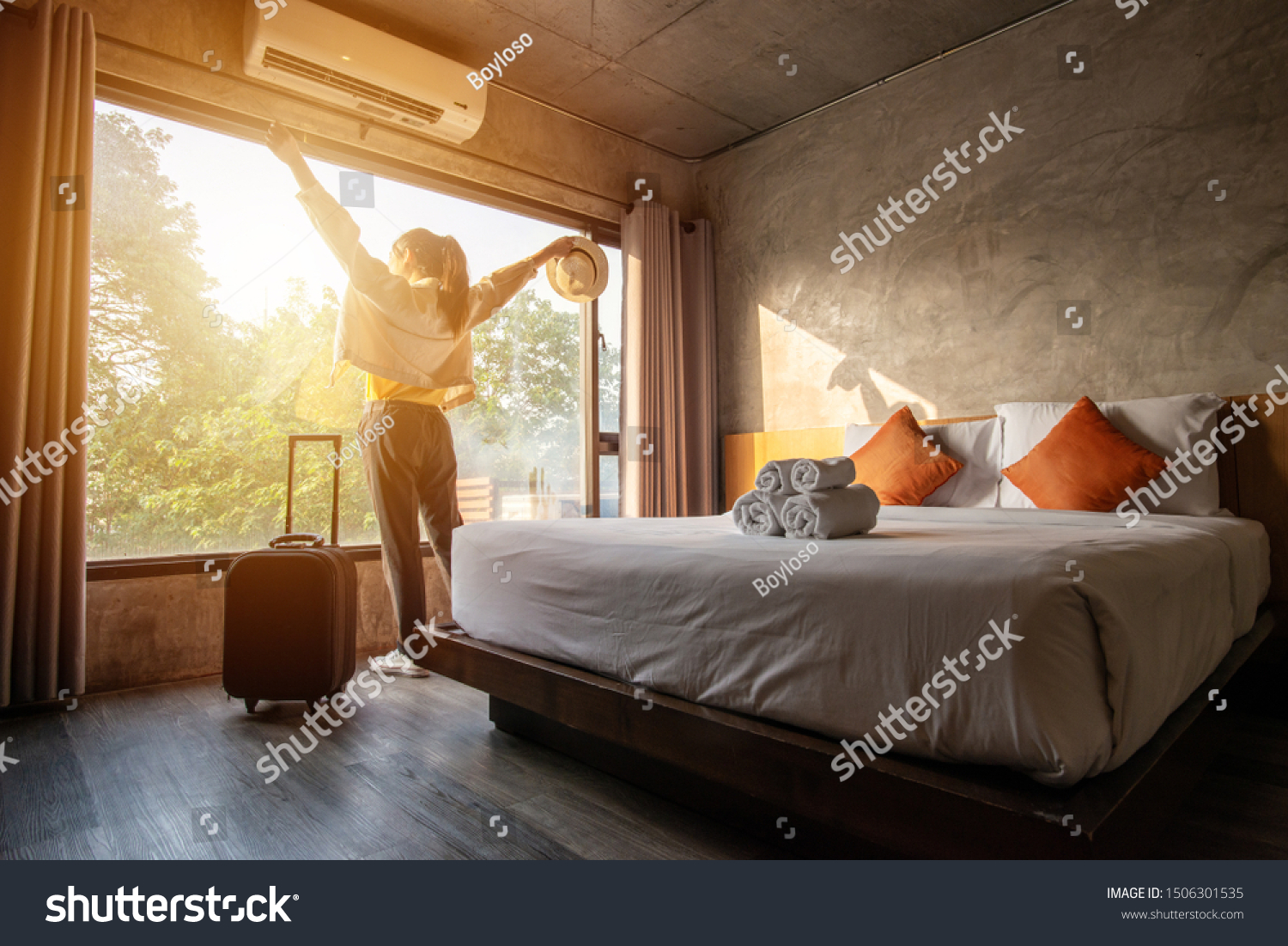 Portrait of tourist woman raised her hands and standing nearly window, looking to beautiful view with her luggage in hotel bedroom after check-in. Conceptual of travel and vacation. #1506301535
