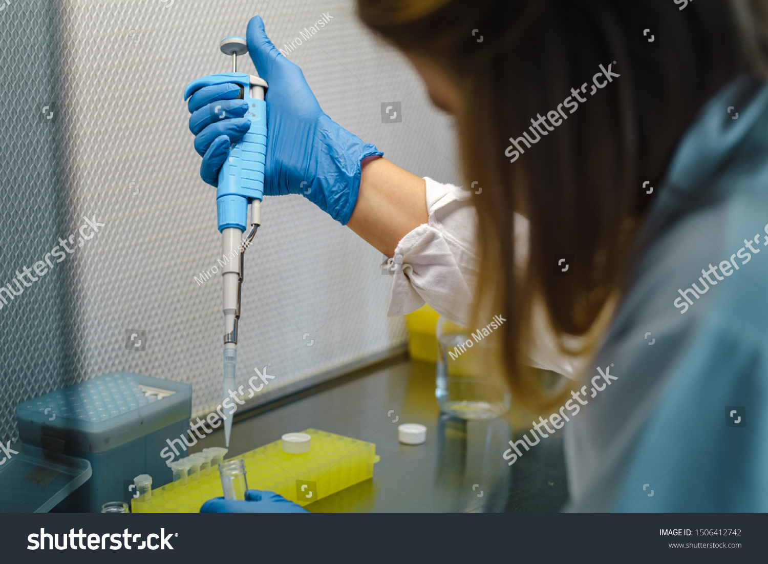 Young woman scientist with gloves and a pipette making experiment in a modern laboratory #1506412742
