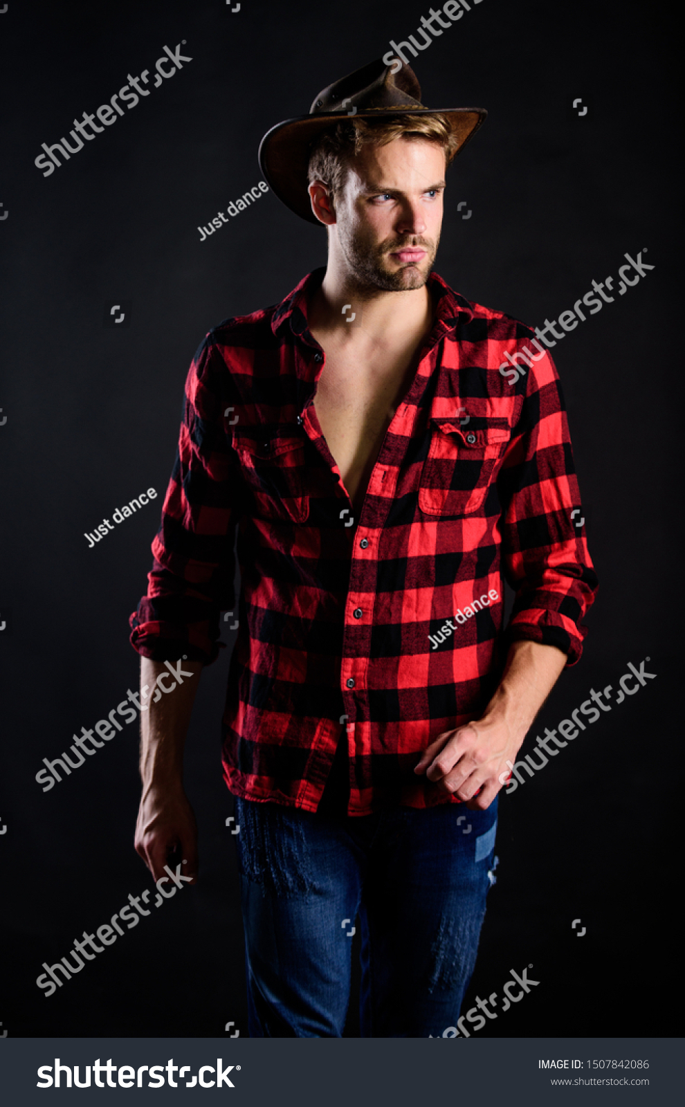 Masculine ideal. Masculinity and brutality concept. Cowboy life came to be highly romanticized. Adopt cowboy mannerisms as a fashion pose. Man unshaven cowboy black background. Western life. #1507842086