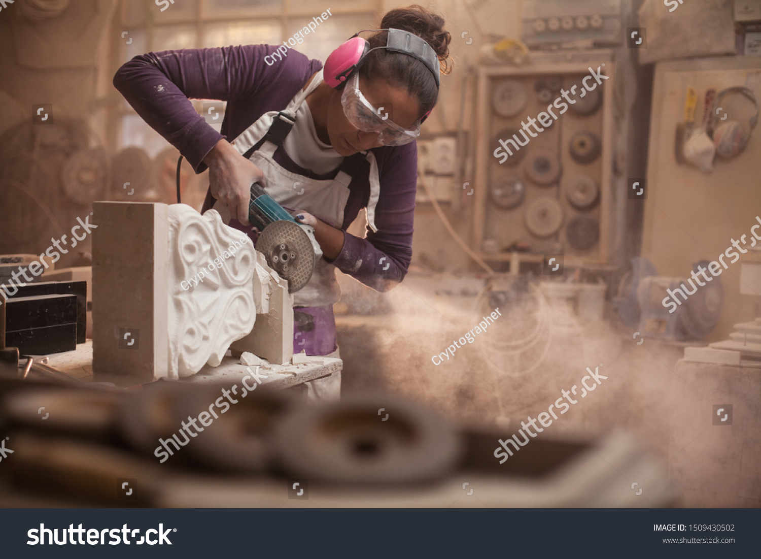 Female stonemason cutting a piece of white marble in a workshop, craftswoman grinding a sculpture with angle grinder, dust and debris flying, women doing hard work concept, stonemasonry and stonecraft #1509430502