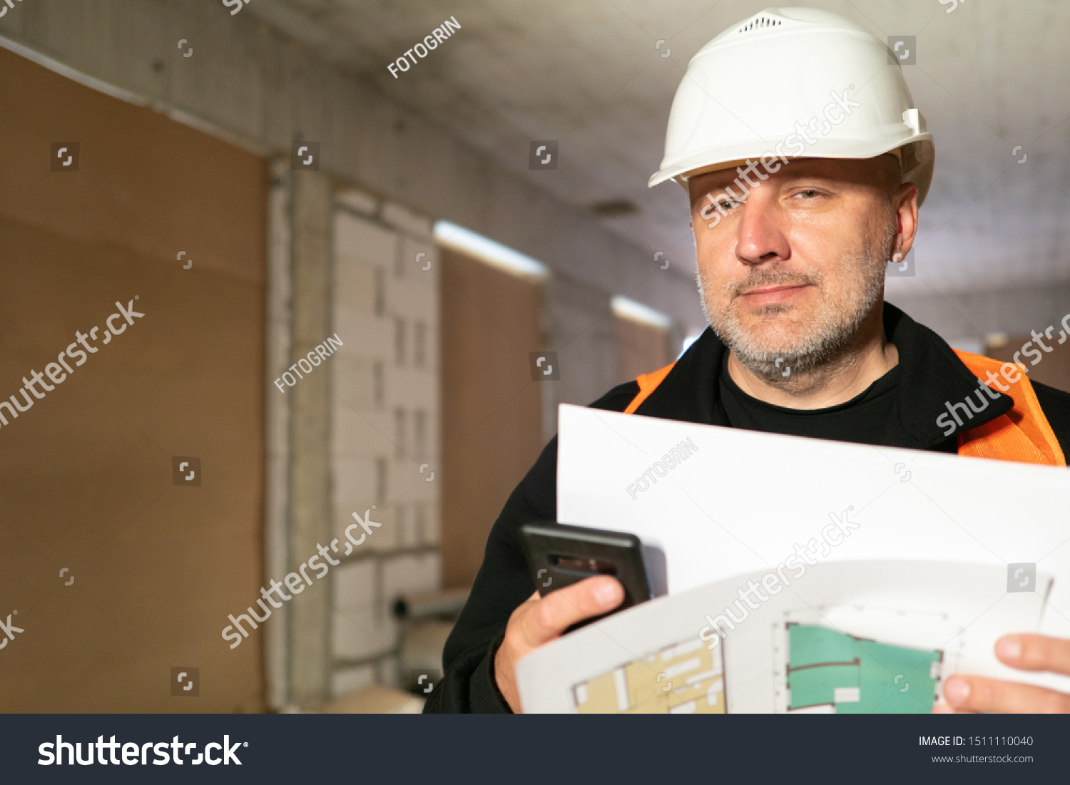 A man in a white helmet in a building under construction. The team leader checks the work of builders. Conformity assessment of construction documentation. Quality assurance. Builder. #1511110040