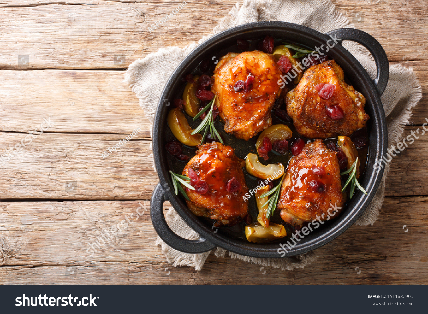 Crispy fragrant baked chicken thighs with apples, cranberries and rosemary closeup in a pan on the table. horizontal top view from above #1511630900