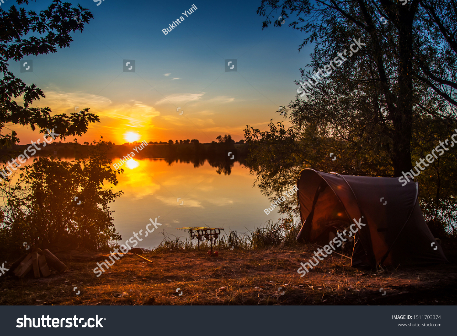 Fishing adventures, carp fishing. Angler, at sunset, is fishing with carpfishing technique. Camping on the shore of the lake.Carp Fishing Sunset #1511703374