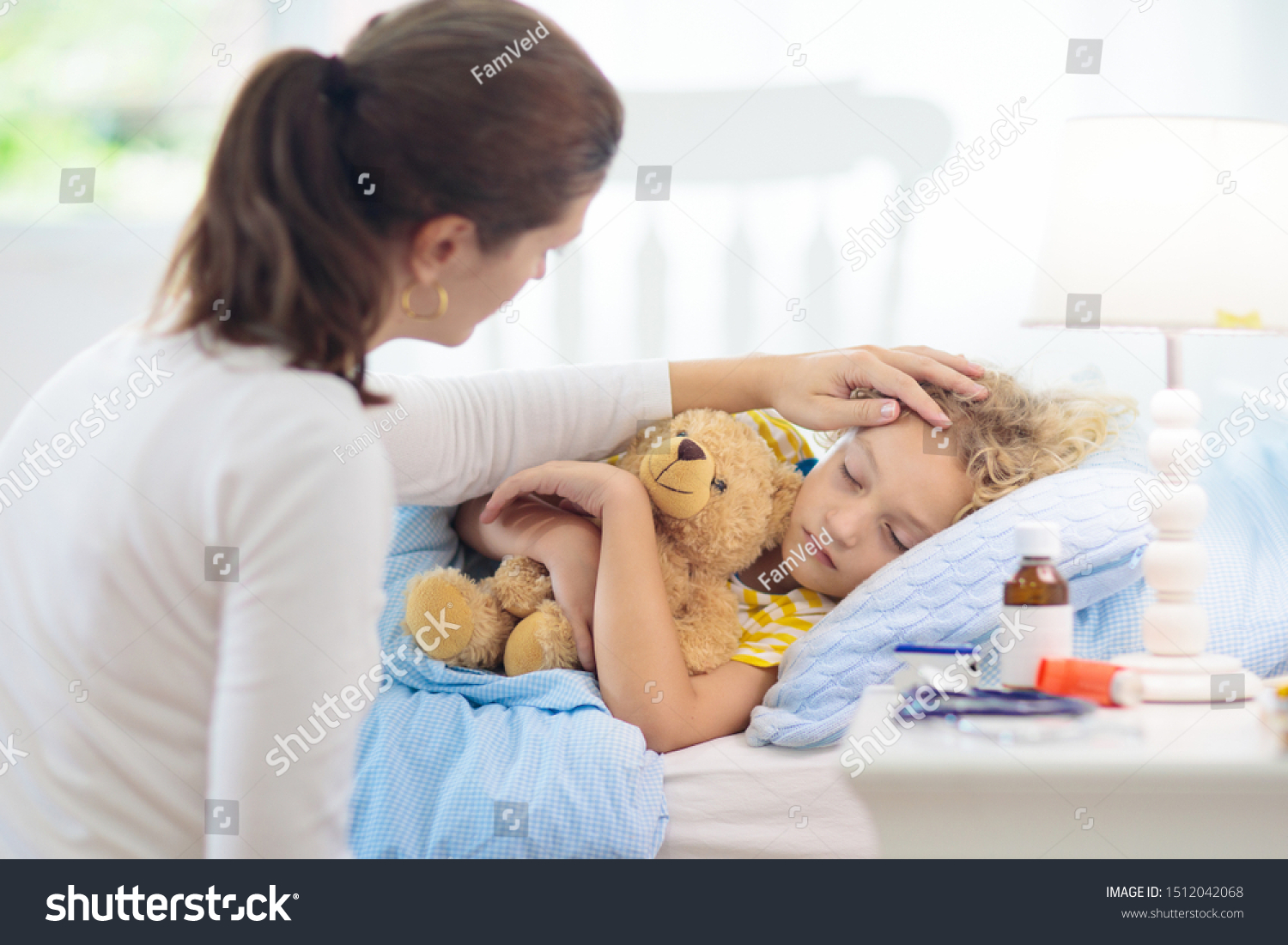 Sick little boy with asthma medicine. Mother with ill child lying in bed. Unwell kid with chamber inhaler for cough treatment. Flu season. Parent in bedroom or hospital room for young patient.  #1512042068