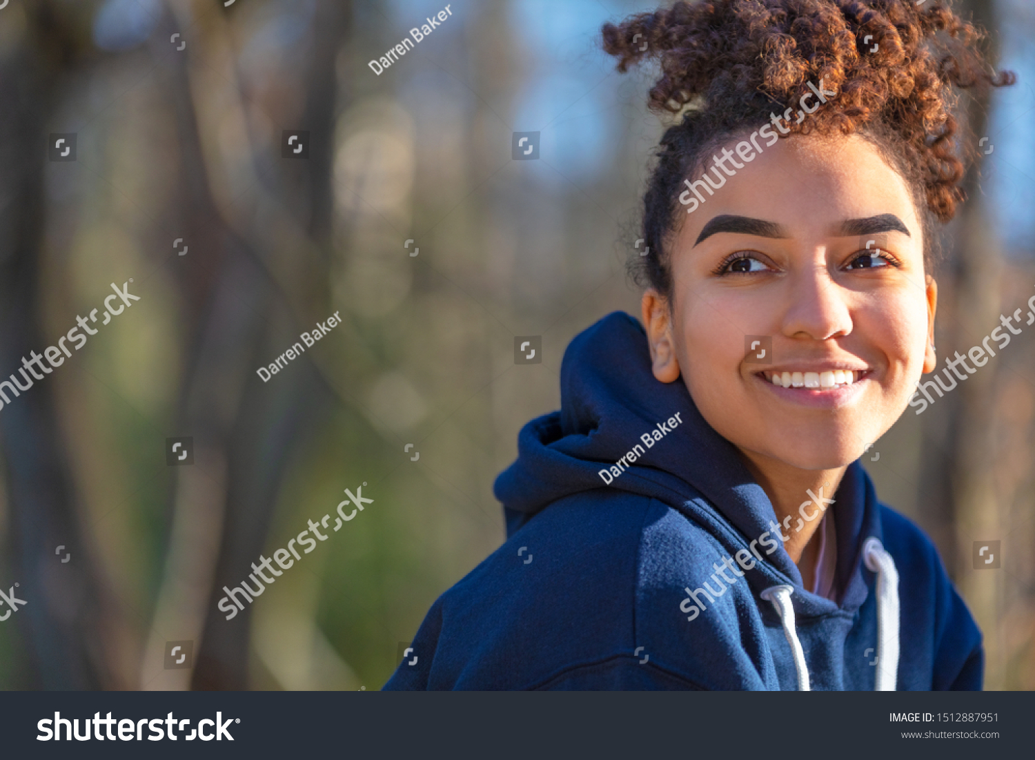 Outdoor portrait of beautiful happy mixed race biracial African American girl teenager female young woman smiling with perfect teeth wearing a blue hoodie #1512887951