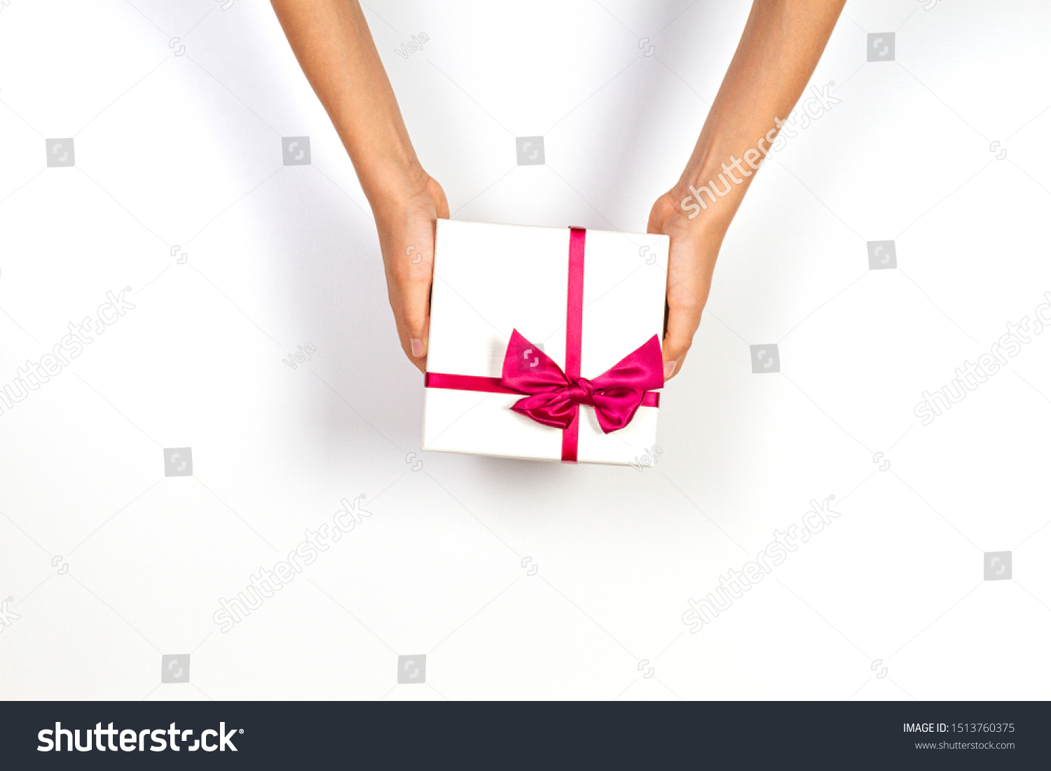 Child hands holding present gift box tied with ribbon on white background. Top view, place for text. Holiday concept #1513760375