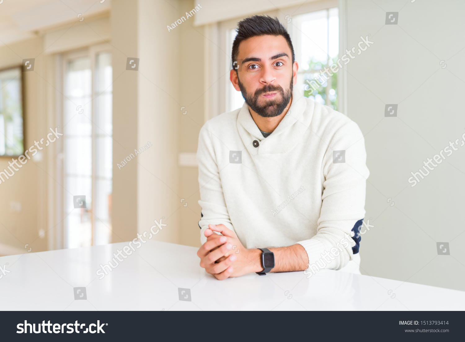 Handsome hispanic man wearing casual white sweater at home puffing cheeks with funny face. Mouth inflated with air, crazy expression. #1513793414