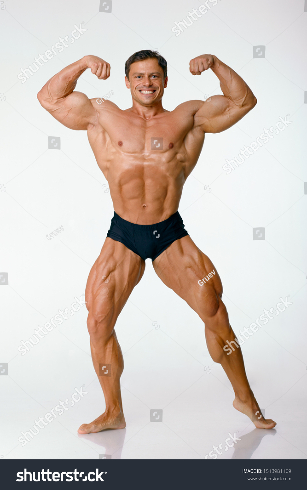 Young athlete, bodybuilder, on a white background in full growth, front view. Biceps, shoulders, torso, legs, sports body, muscle posing #1513981169