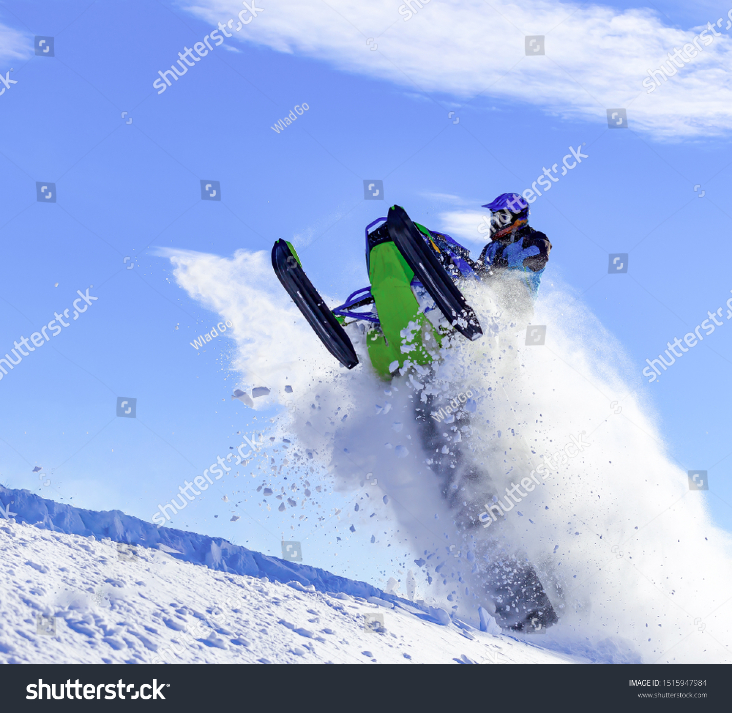 the guy is flying and jumping on a snowmobile on a background of blue sky leaving a trail of splashes of white snow. bright snowmobile and suit without brands. extra high quality #1515947984