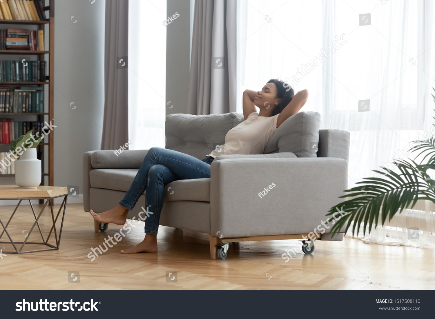 In modern living room peaceful african woman resting leaned on sofa closed eyes put hands behind head feels placidity enjoy weekend or vacation, inner harmony, no stress anxiety fatigue relief concept #1517508110