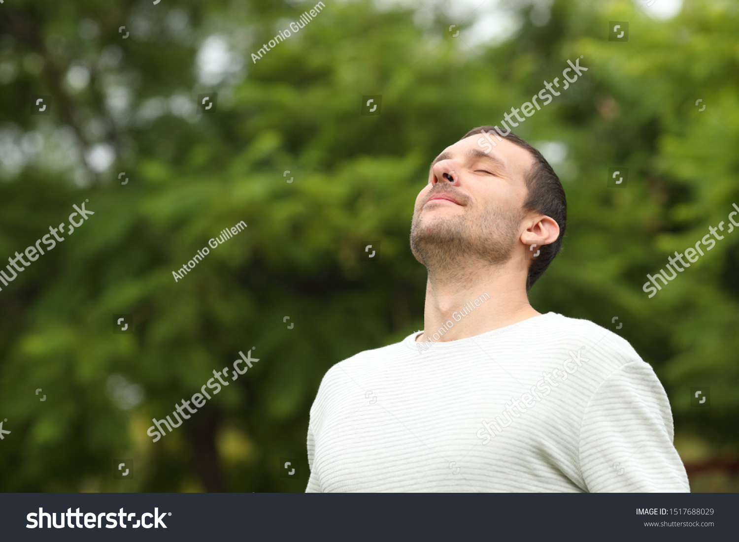 Relaxed adult man breathing fresh air in a forest with green trees in the background #1517688029