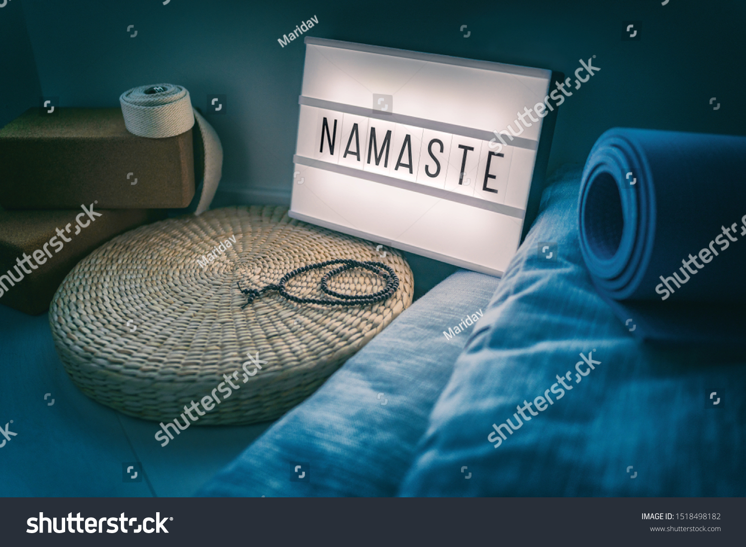 Yoga studio class sign lightbox with letters writing NAMASTE glowing in the night light with natural accessories, rubber mat, cork blocks, organic cotton strap and pillows, straw meditation pillow. #1518498182