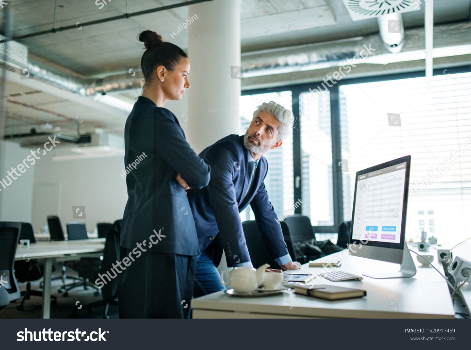 Two businesspeople with computer standing in an office at desk, working. #1520917469