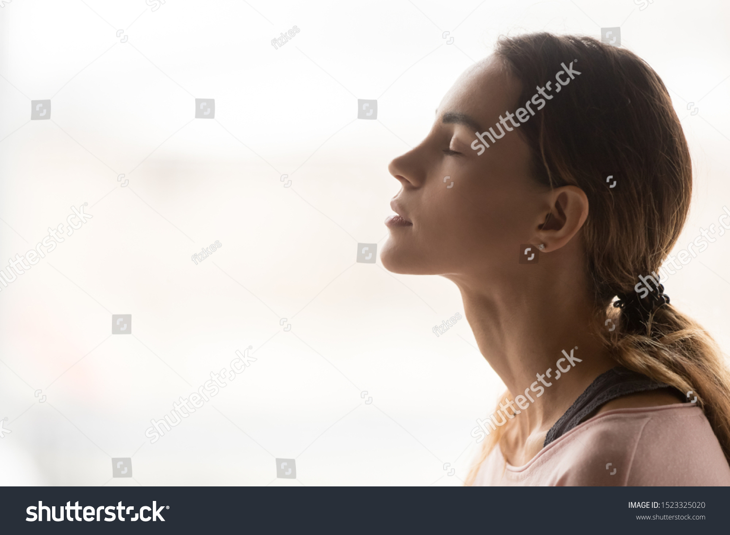 Serene young woman taking deep breath of fresh air relaxing meditating with eyes closed enjoying peace, calm girl tranquil face doing yoga pranayama exercise feel no stress free relief, side view #1523325020