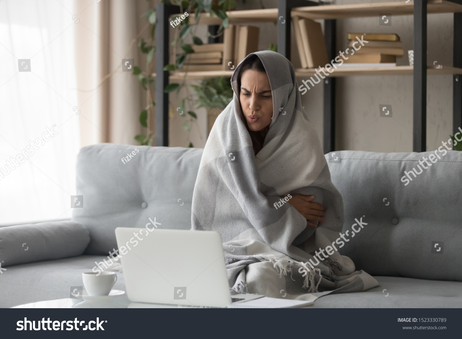 Sick ill young woman feel cold covered with blanket sit on sofa watching movie on laptop, annoyed girl shiver freezing warming at home wrapped with plaid, no central heating problem and flu concept #1523330789