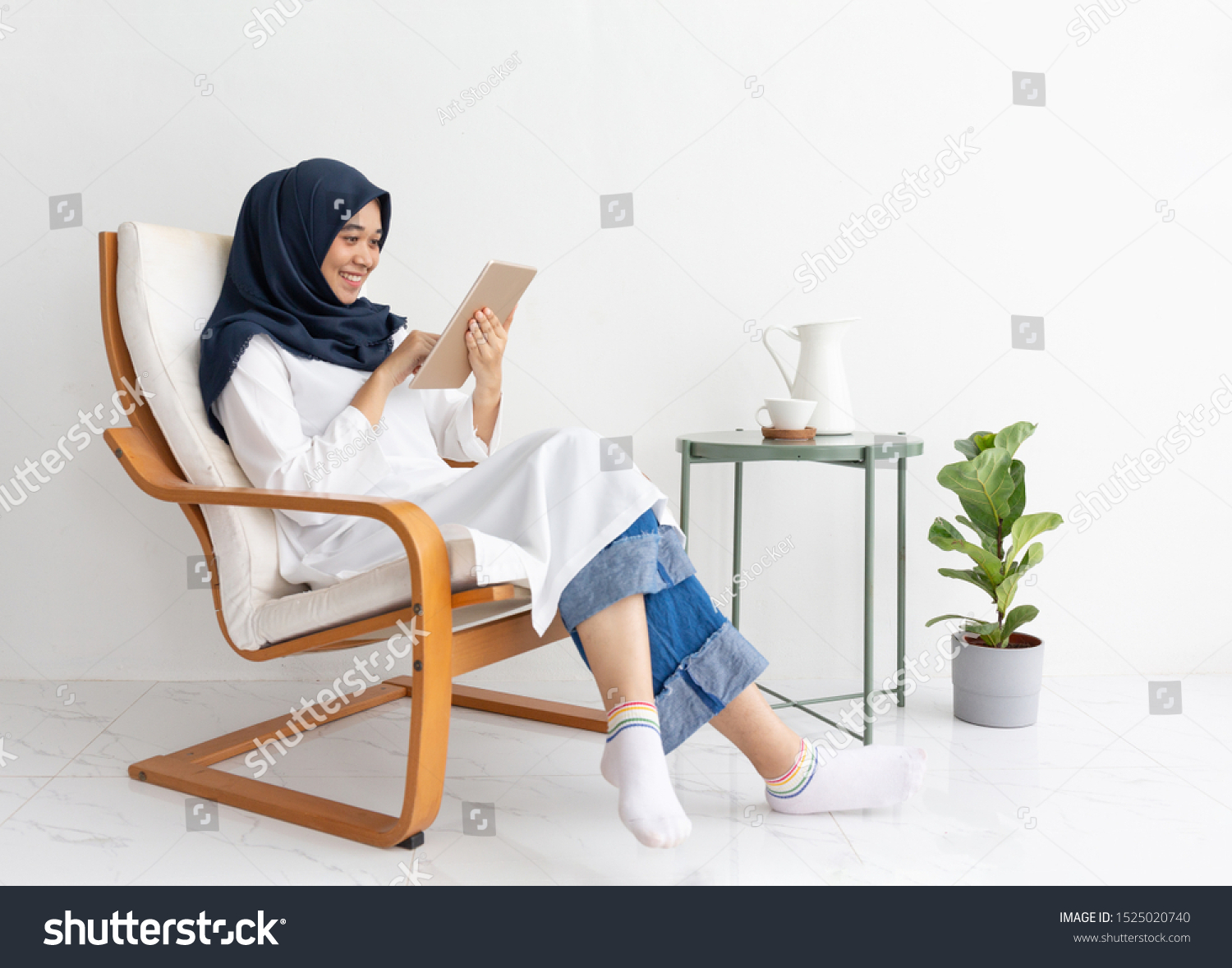 Young muslim Indonesia asian woman happy on tablet casual home chair. Malay lady journalist sit Hijab girl Islam business on phone smartphone mobile online. Ramadan Malaysia family video call isolate. #1525020740