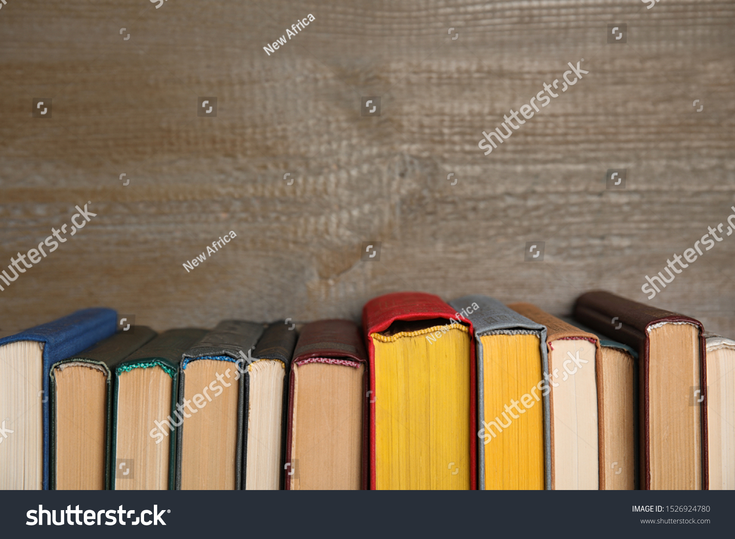 Stack of hardcover books on wooden background. Space for text #1526924780