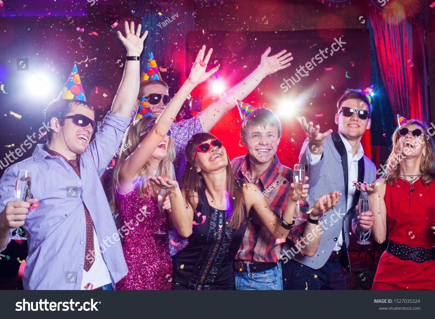 Cheerful young people showered with confetti on a club party. #1527035324