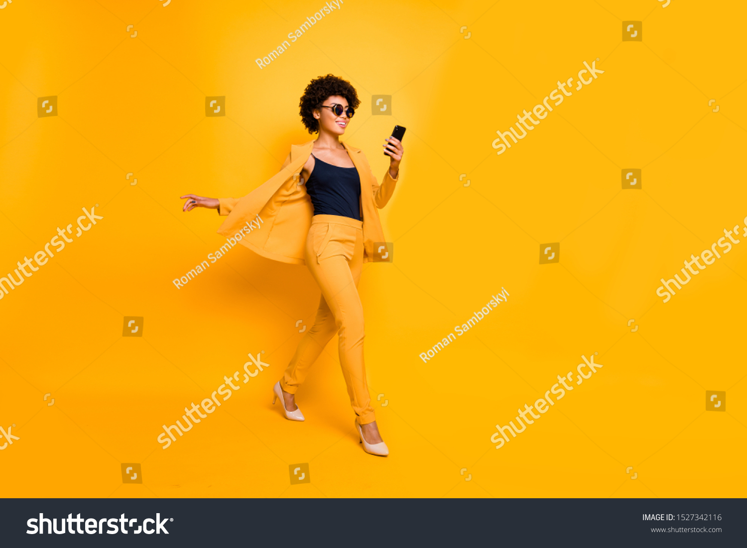 Full length profile side photo of positive afro american have spectacles weekend go use smartphone type sms on social network wear style outfit pants high-heels isolated yellow color background #1527342116