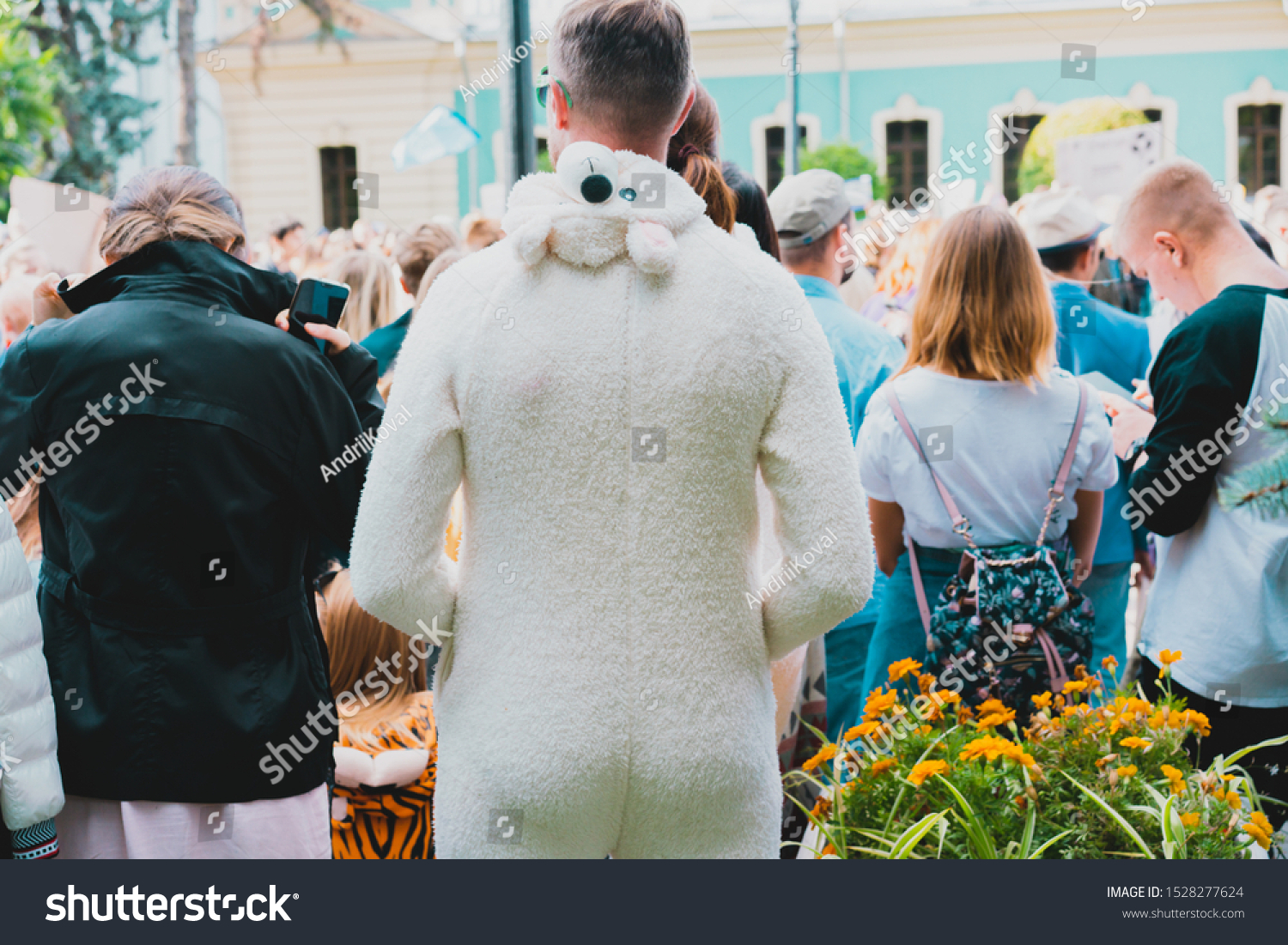 Man wears white bear costume in crowd. Back of male in a costume. Be yourself concept. Wearing pajamas in the city #1528277624