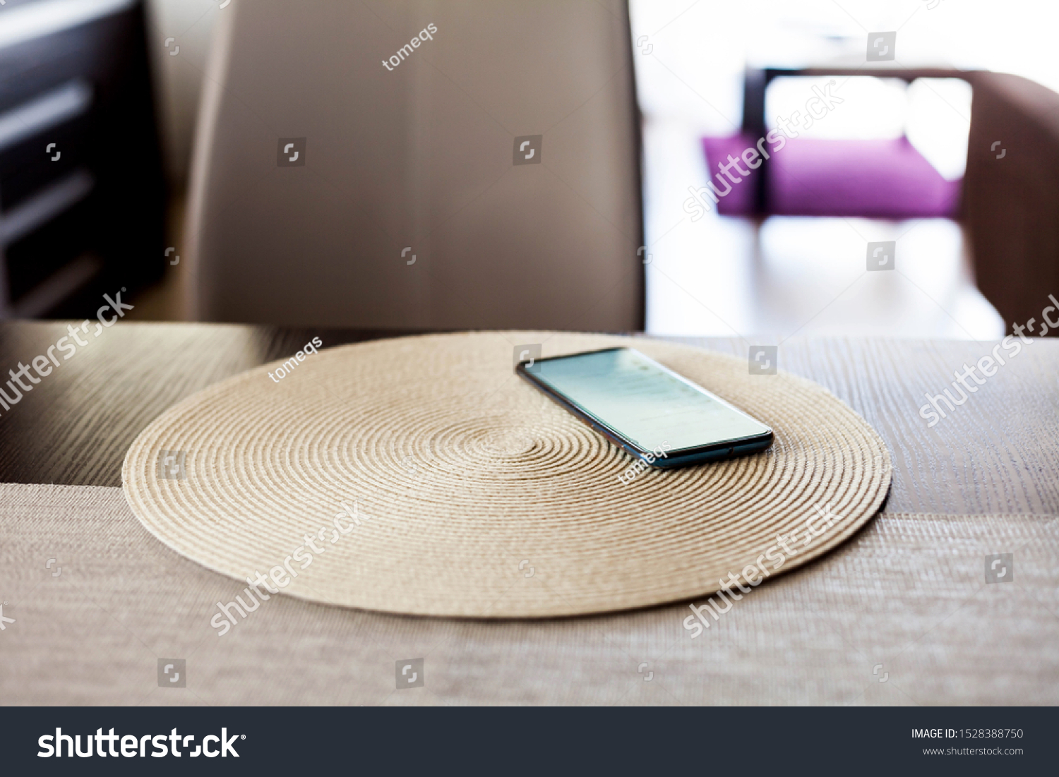 Single smartphone left on the table in the living room, one unattended mobile phone device laying on a coaster screen on scene data security, leaving your tech on the table concept.  Copy space nobody #1528388750