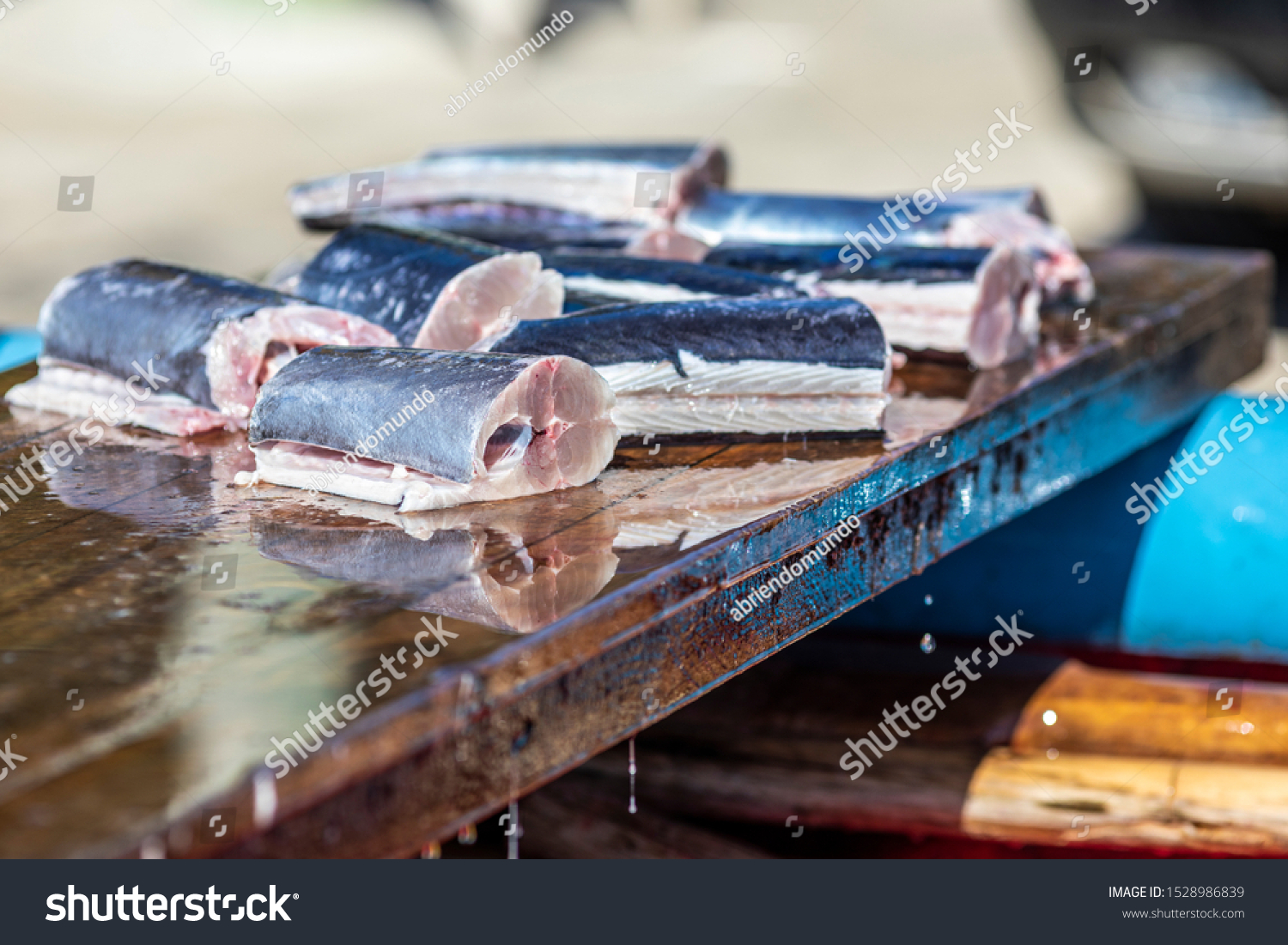 Some slices of fresh fish above a wooden table inside a fishermen boat. Traditional healthy food tempting our eyes with it freshness. A delicious freshly caught swordfish #1528986839
