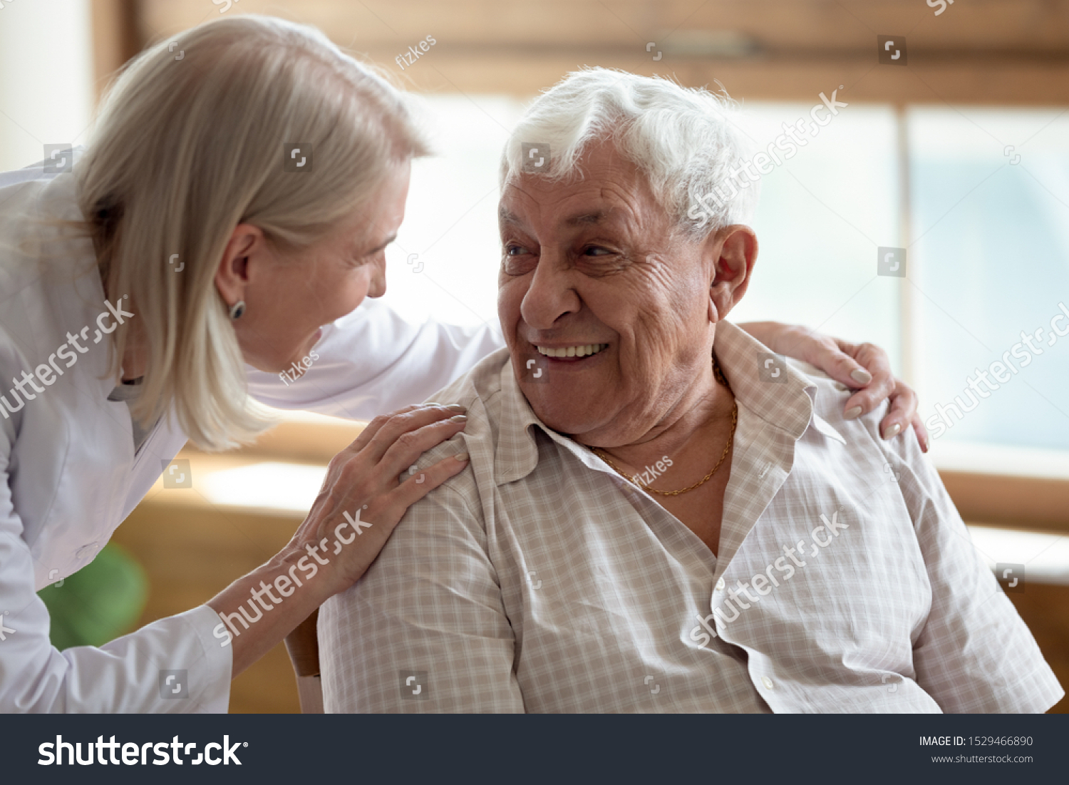 Caring middle-aged female licensed practical nurse in white coat talk to elderly patient 80s man, worker care about old healthcare consumer listens complaints give support, caregiving service concept #1529466890