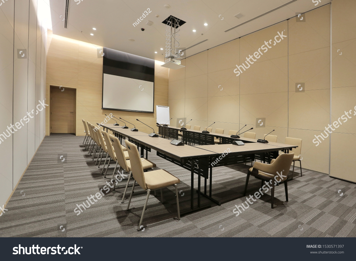 Interior of modern fully equipped professional facilities meeting conference room boardroom classroom office with nobody empty and  microphones white projector board chairs door business meeting venue #1530571397