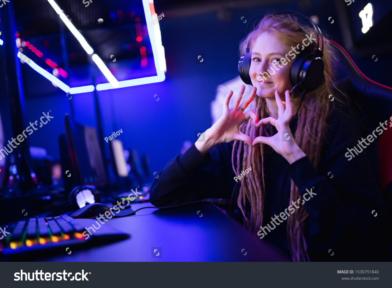Streamer beautiful girl shows heart sign with hands professional gamer playing online games computer, neon color. #1530791840