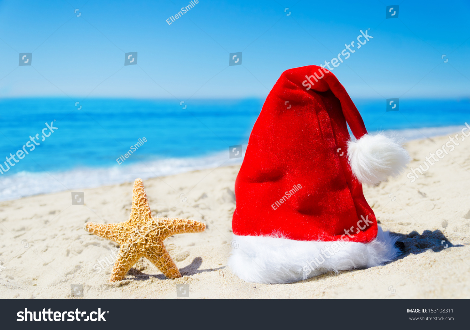 Close up Santa hat with starfish on the beach by the ocean - Christmas and new year concept #153108311