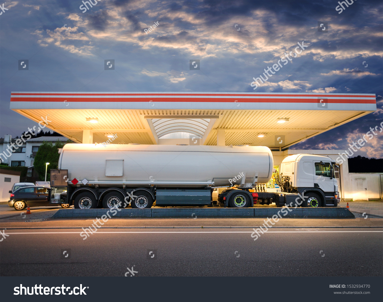 Tanker gas truck delivering fuel at service station against dramatic night sky #1532934770