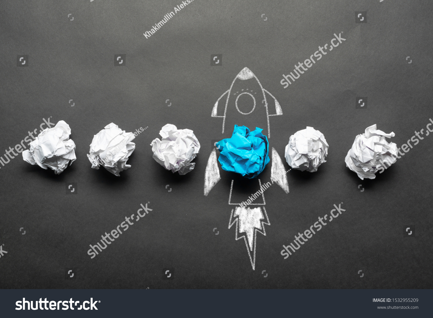 Rocket sketch drawing with crumpled blue paper ball on chalkboard. Successful business startup. Creative motivation with copy space. Unique business idea among failing ideas metaphor. #1532955209
