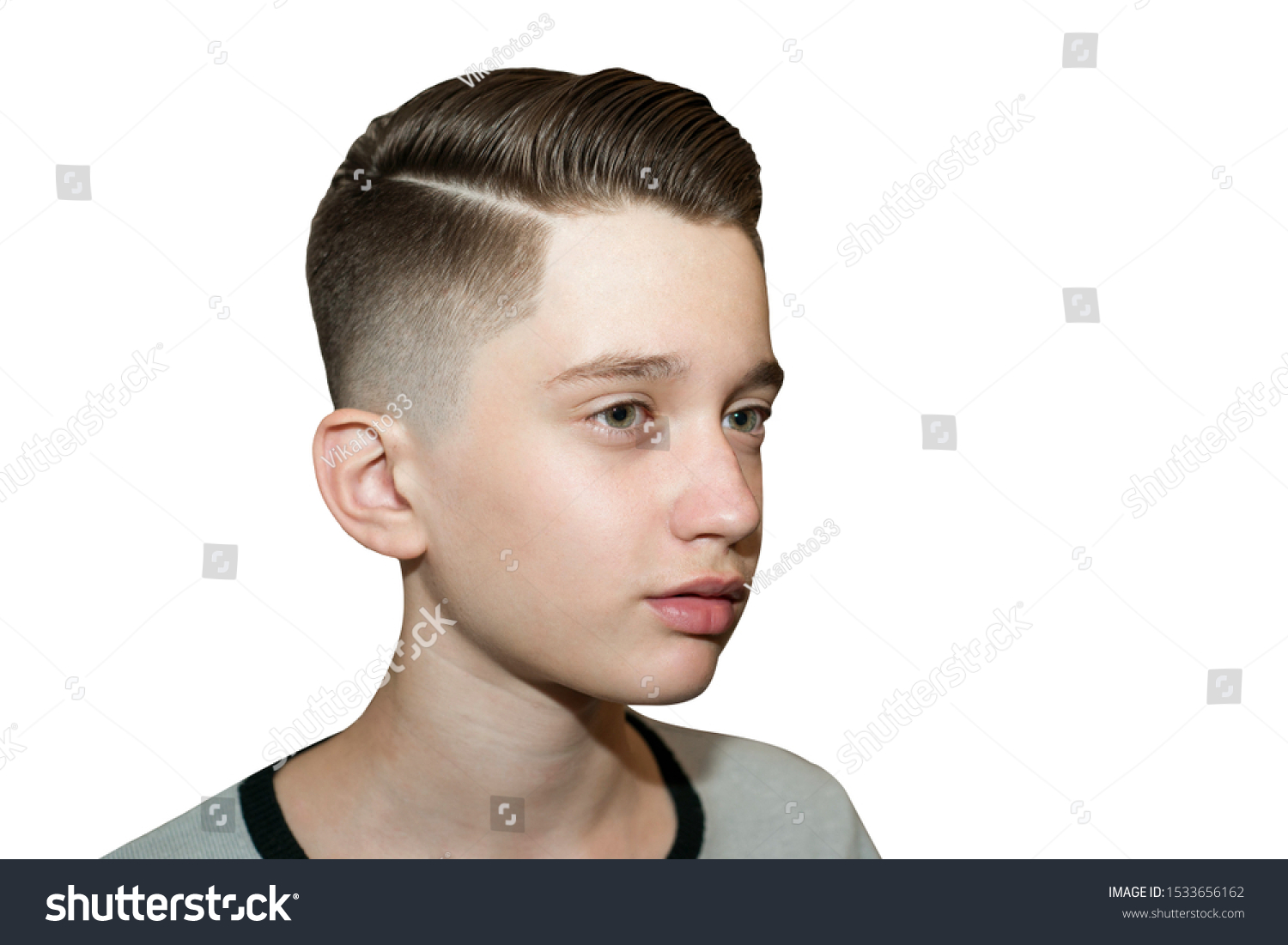 Stylish modern retro haircut side part with mid fade with parting of a schoolboy guy in a barbershop on isolated white background #1533656162