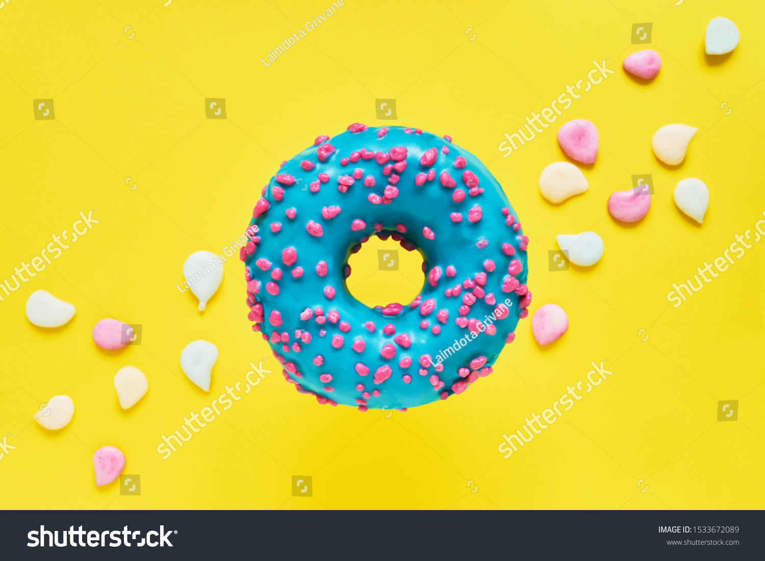 Sprinkled Blue Donut. Glazed sprinkled donut on bright yellow background with colorful candies. Top view, copy space #1533672089