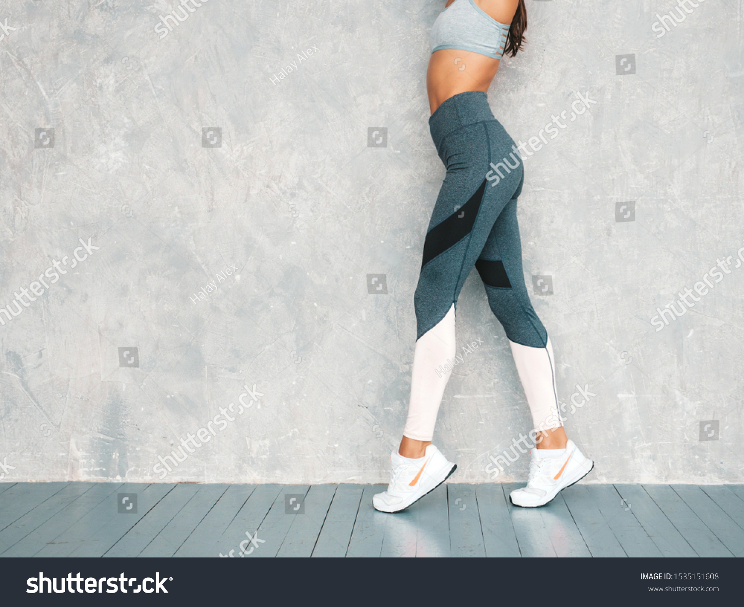 Portrait of fitness woman in sports clothing looking confident.Young female wearing sportswear. Beautiful model with perfect tanned body.Female posing in studio near gray wall #1535151608